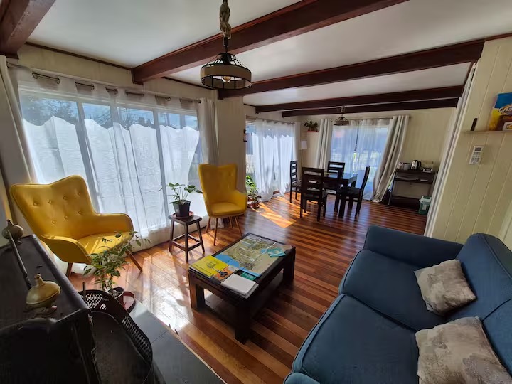 Sala de estar con vigas de madera, sillón amarillo y sofá azul